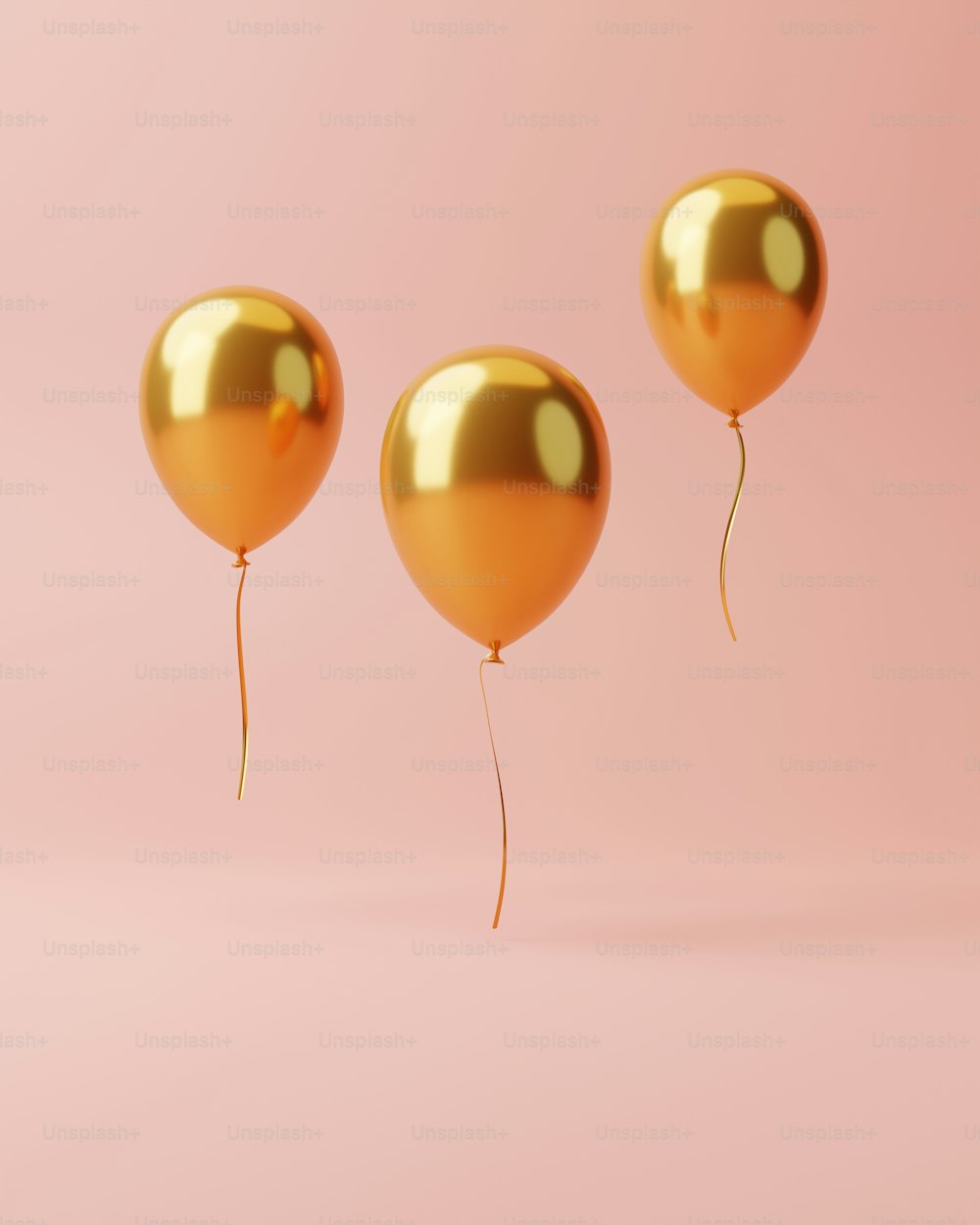 three gold balloons floating in the air