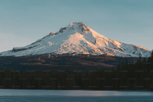a large snow covered mountain towering over a lake