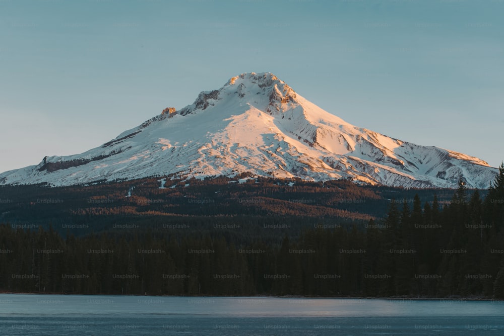 a large snow covered mountain towering over a lake