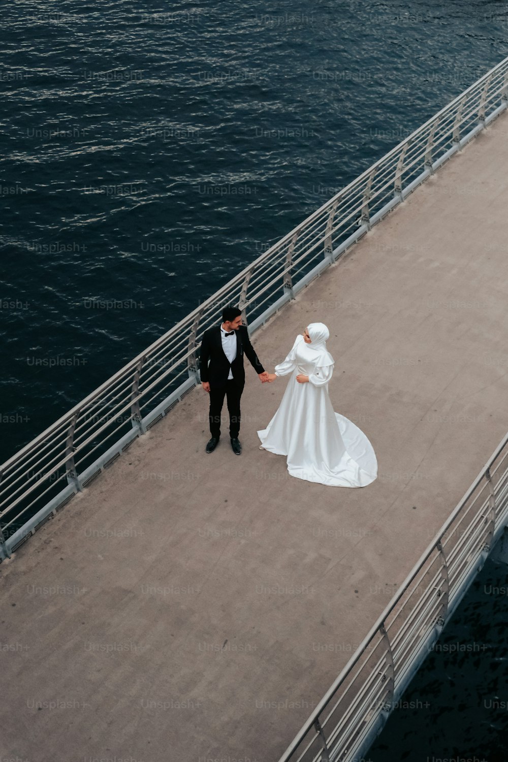 a bride and groom walking on a pier