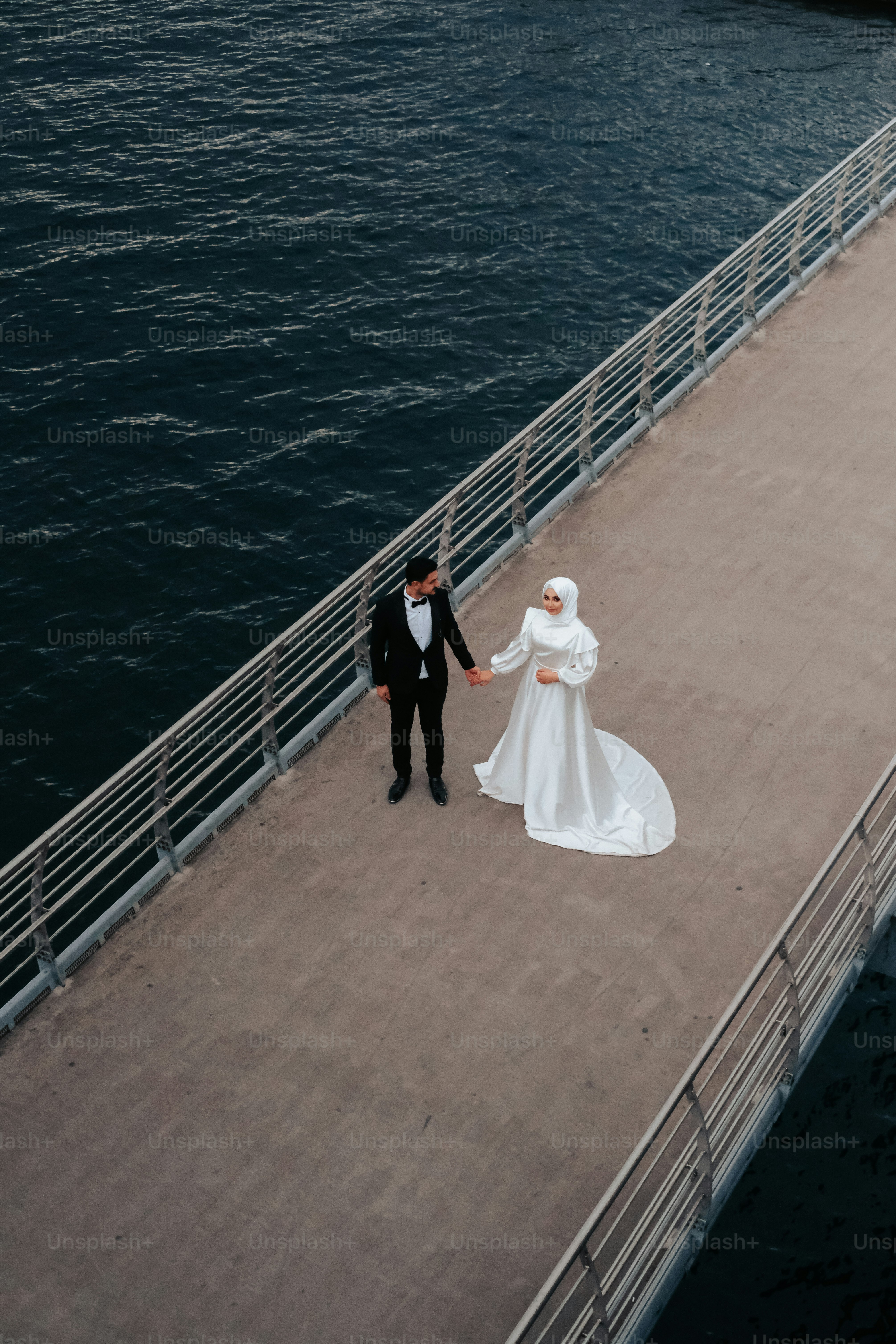 a bride and groom walking on a pier