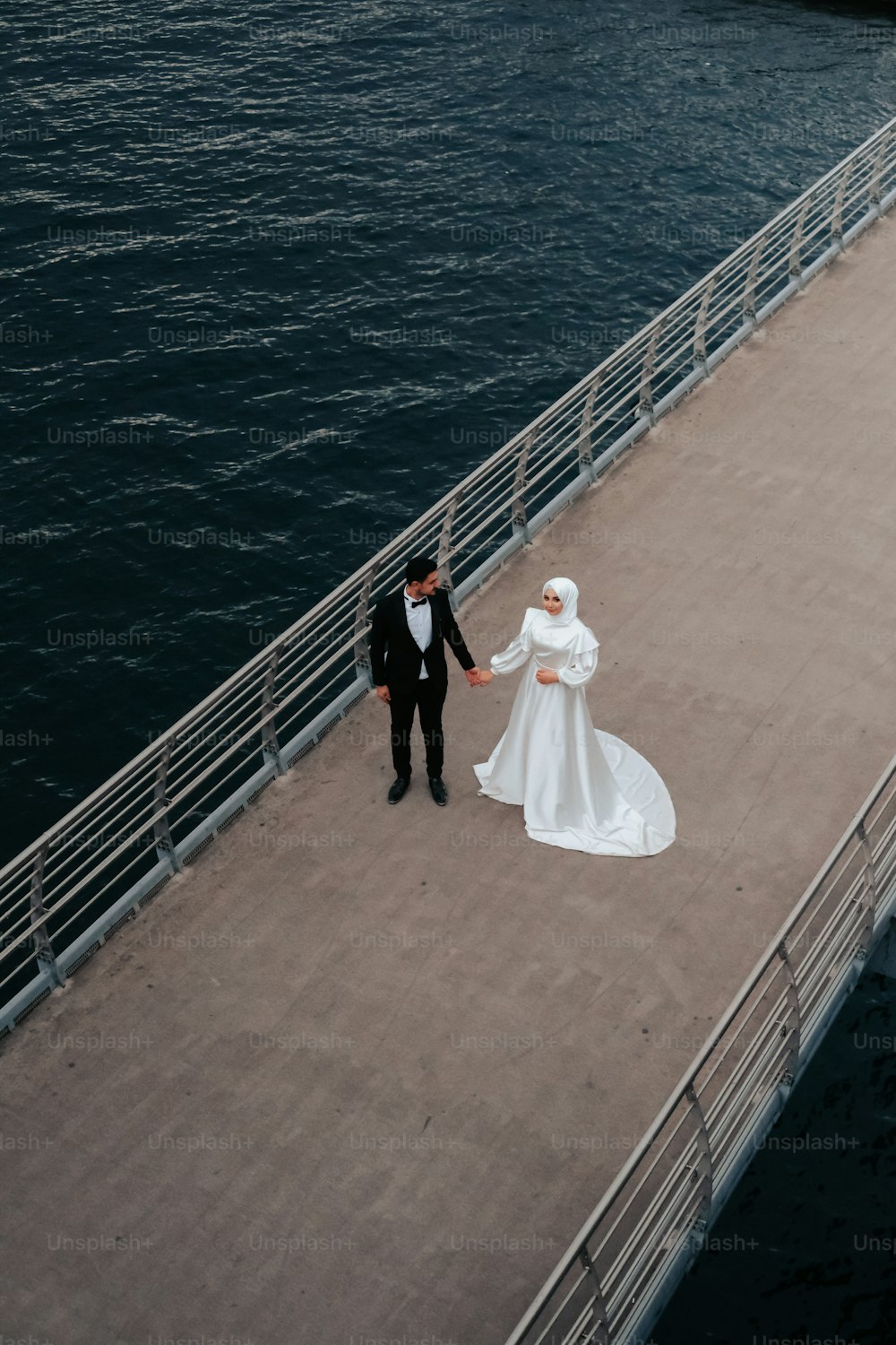 Una sposa e uno sposo che camminano su un molo