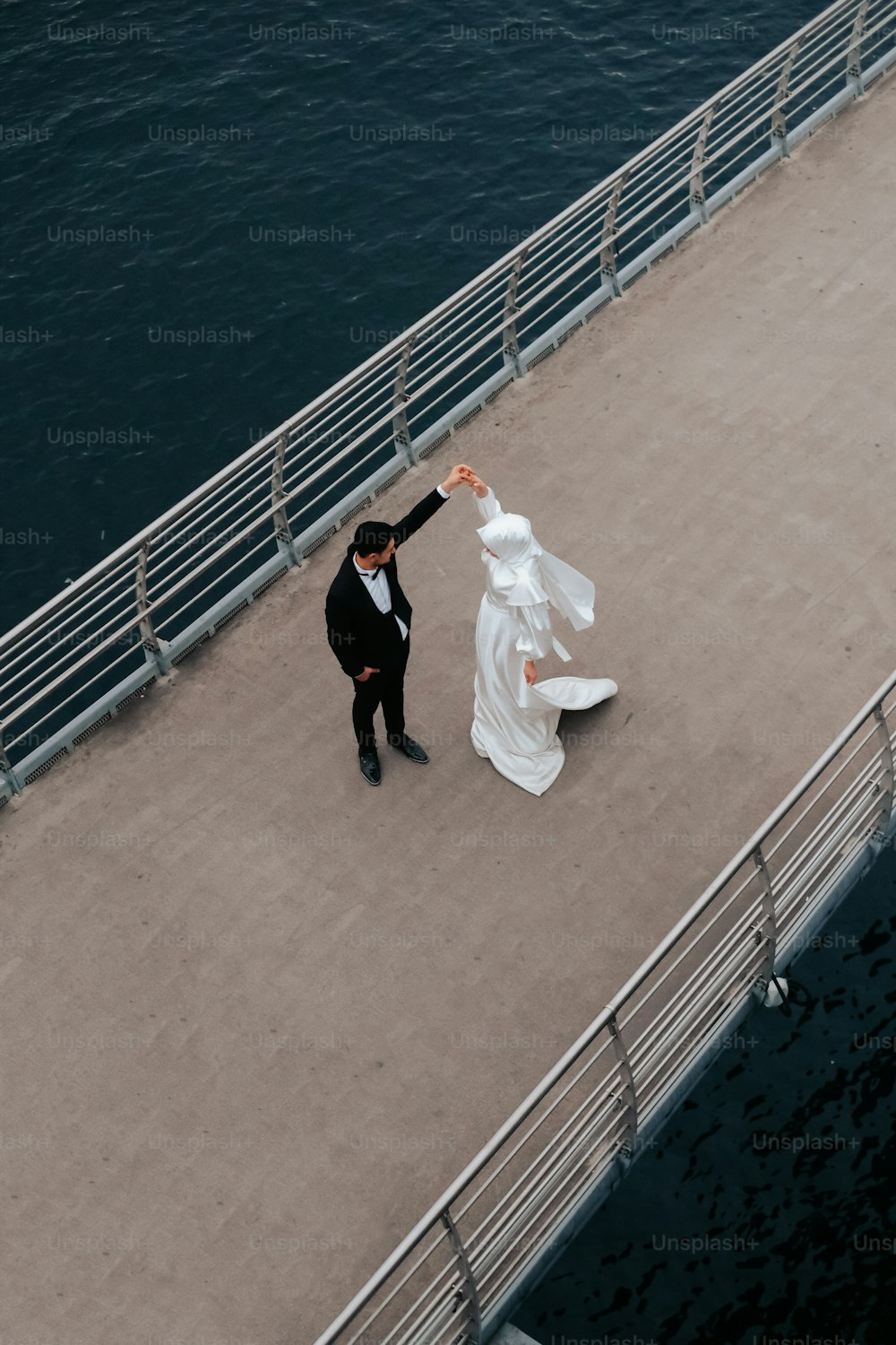 a bride and groom dancing on a pier