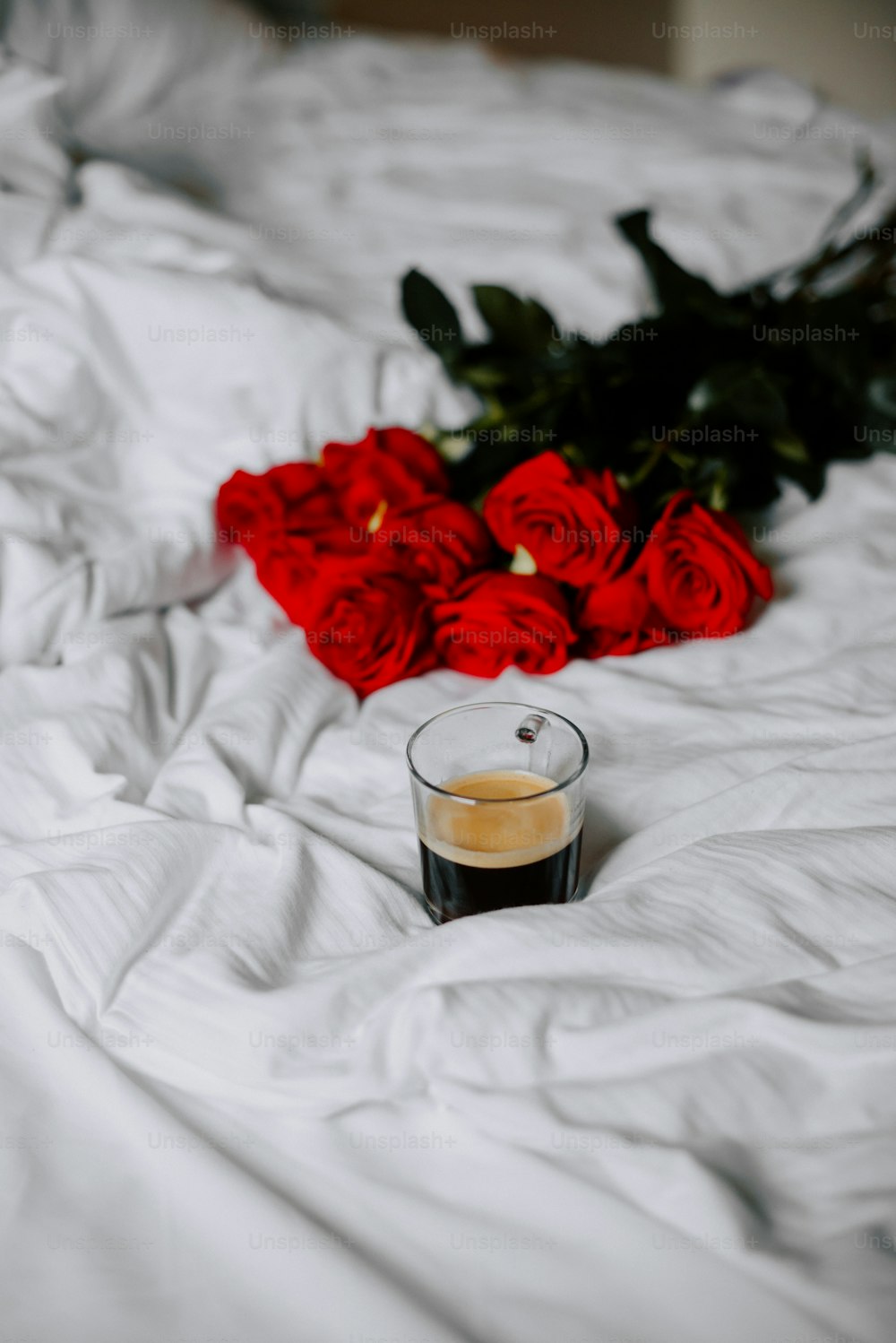 a cup of coffee sitting on top of a bed
