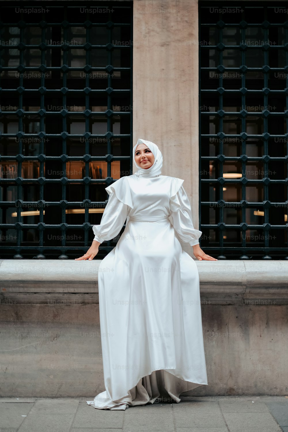 Una donna in un vestito bianco in piedi su un marciapiede