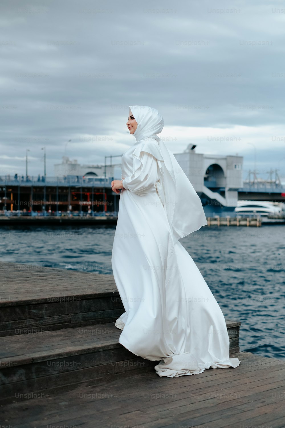 a woman in a white dress standing on a dock