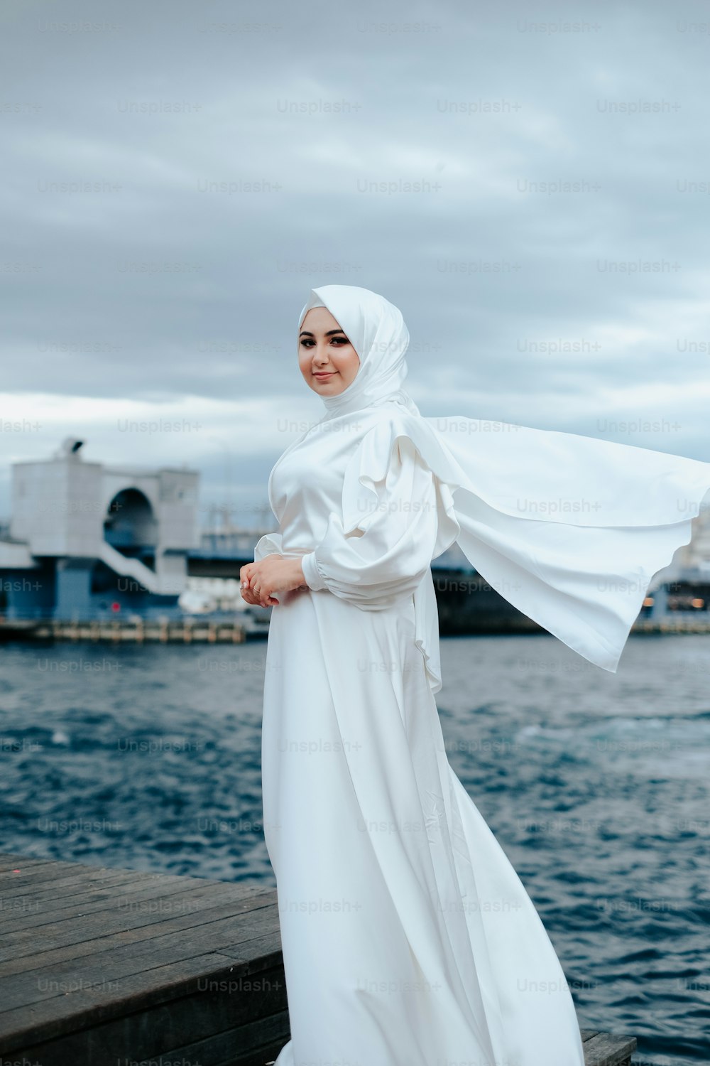 Una donna in un vestito bianco in piedi su un molo