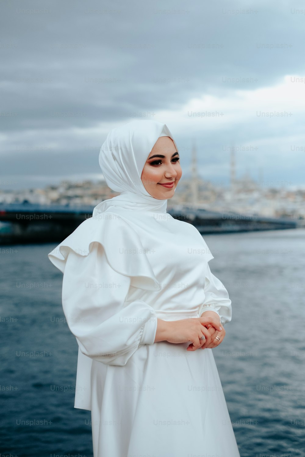 a woman in a white hijab standing by the water