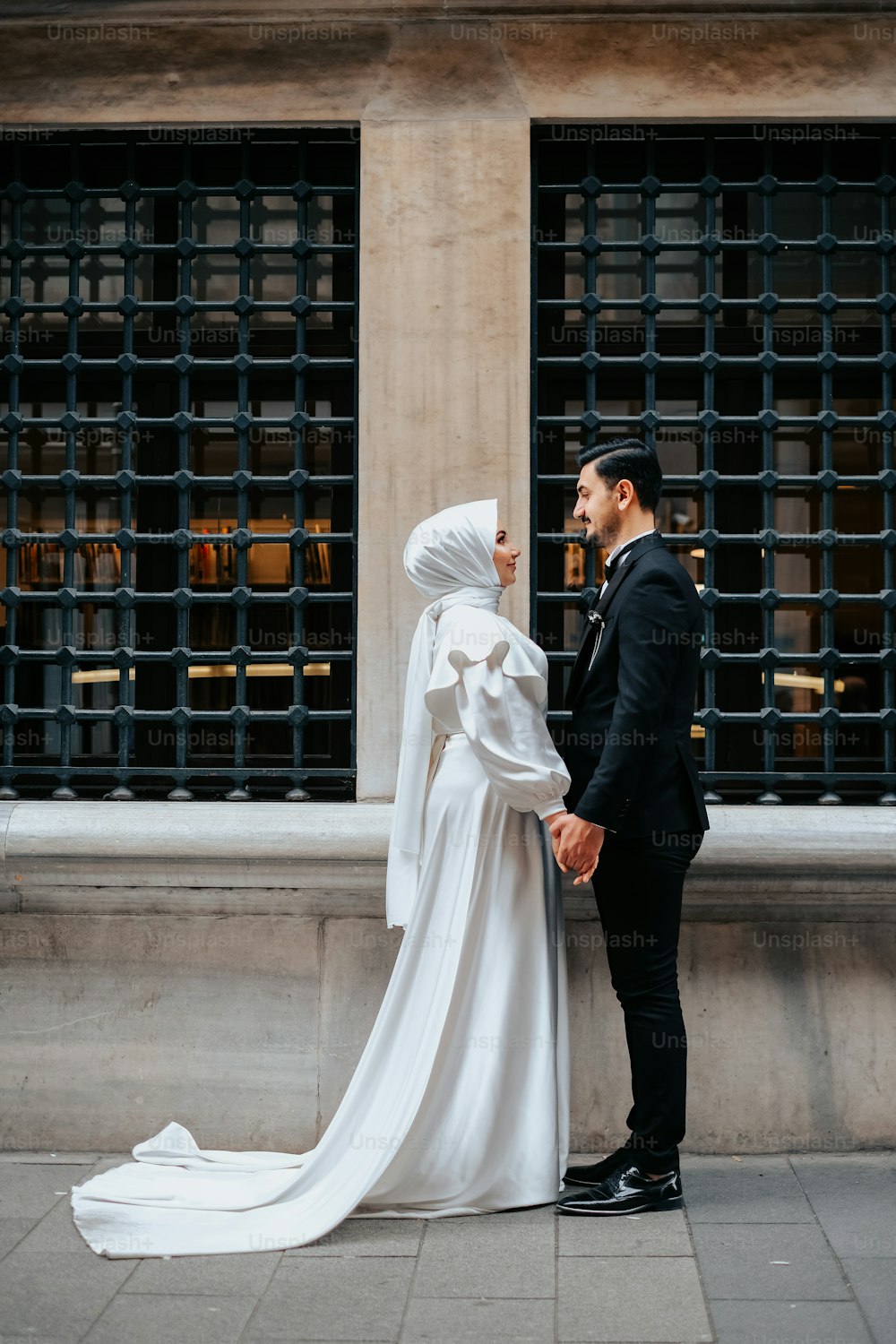 Una sposa e uno sposo in piedi uno accanto all'altro di fronte a un edificio