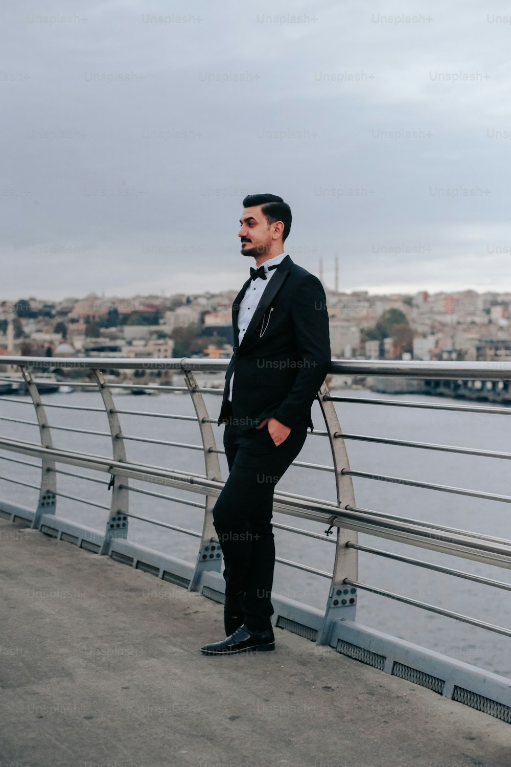 a man in a tuxedo standing on a bridge