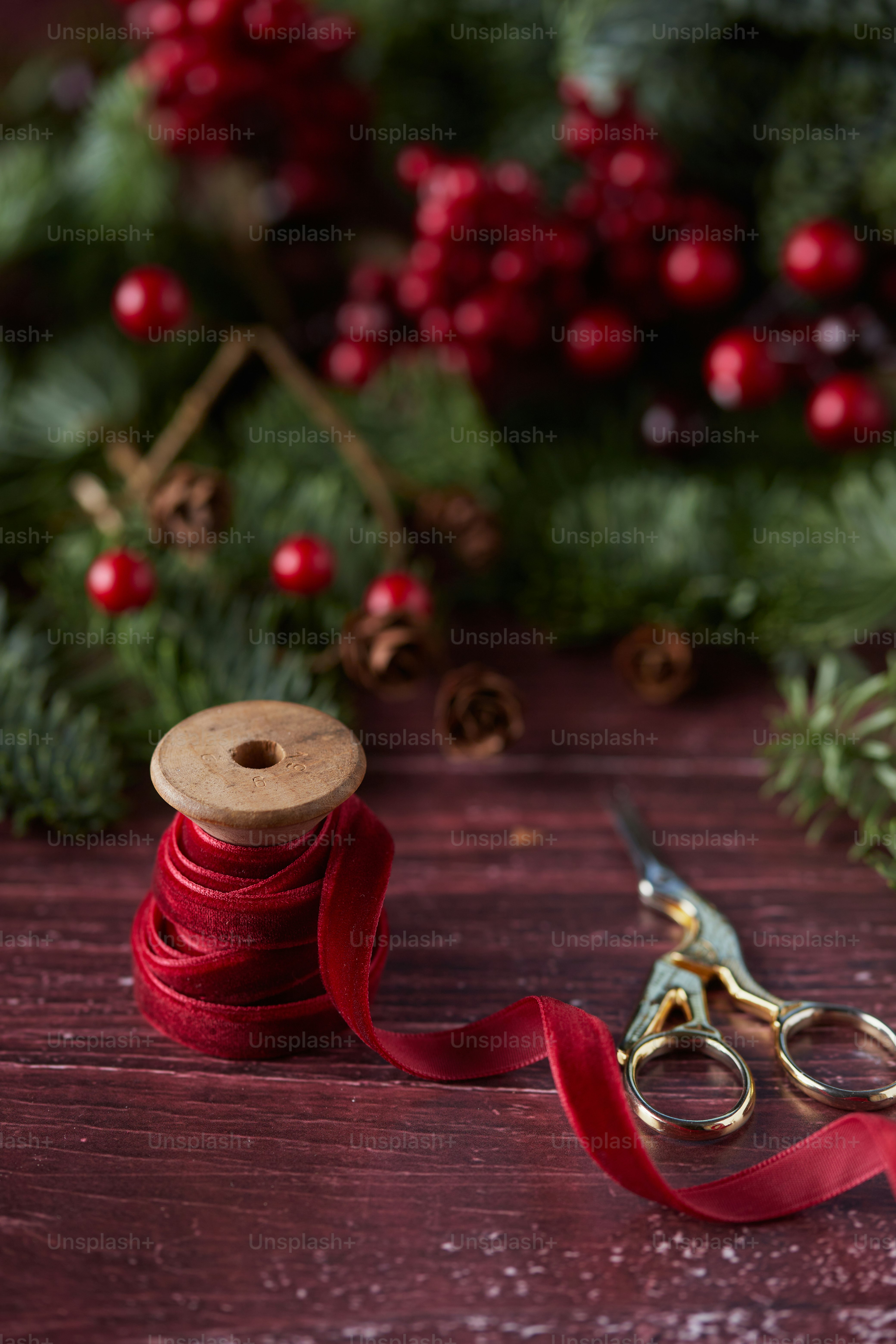 a spool of red ribbon next to a pair of scissors