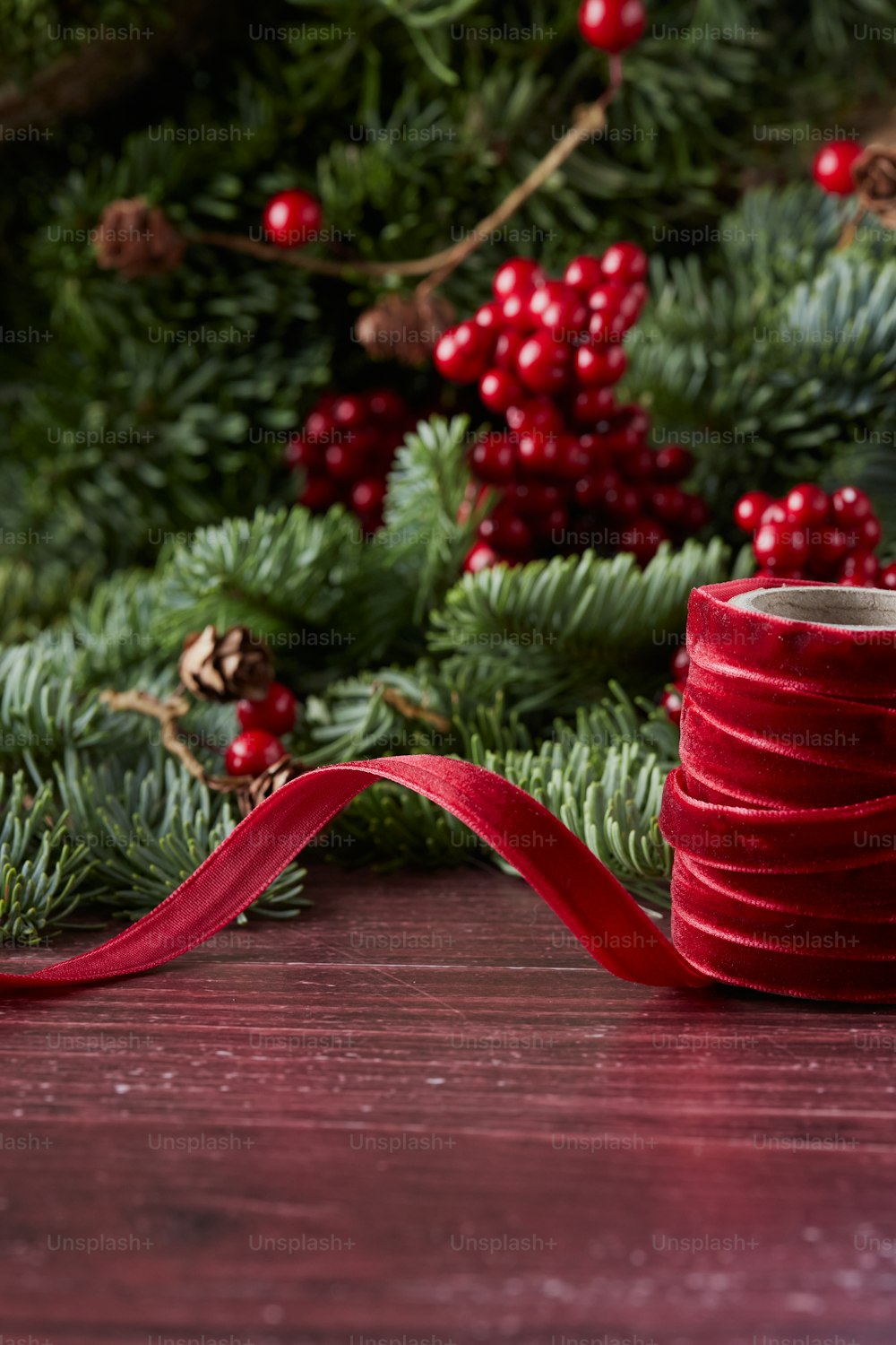 a roll of red ribbon sitting on top of a wooden table