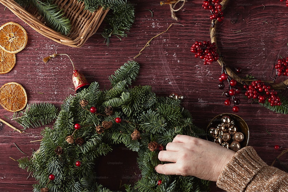 Una mano sosteniendo un reloj plateado junto a un árbol de Navidad