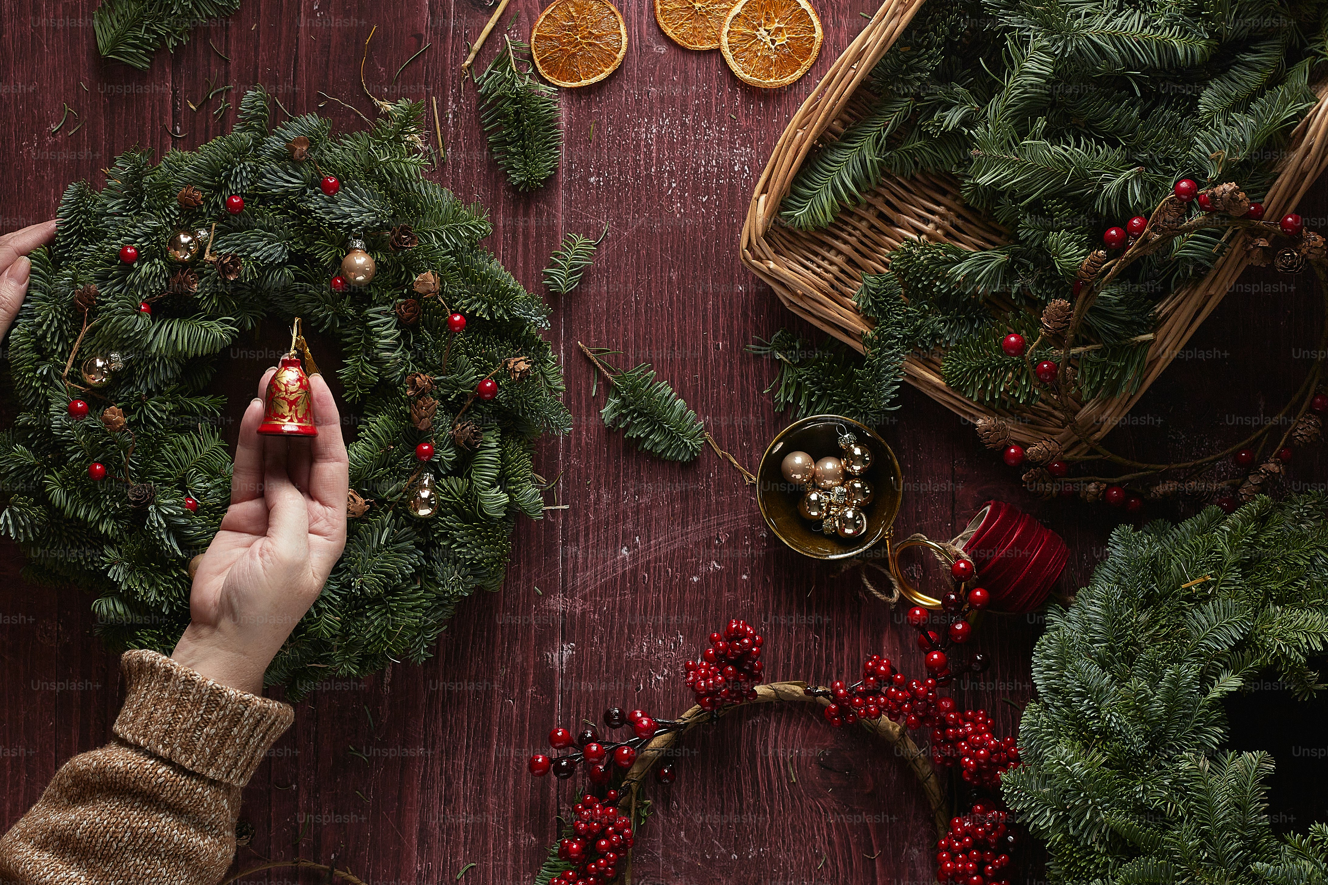 a hand holding a gold ball in front of a decorated tree