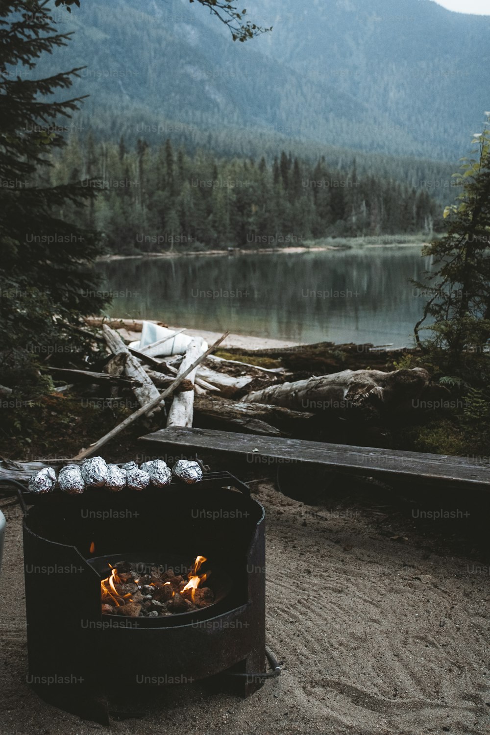 a fire pit with a fire in it by a lake and trees