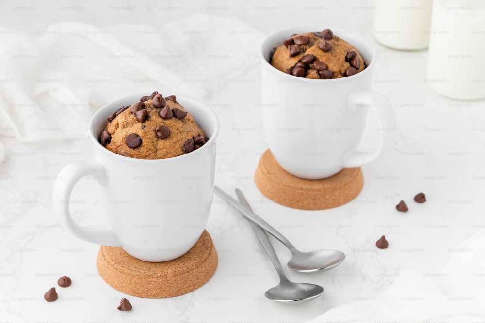 a couple of cups with coffee beans and a cookie in it