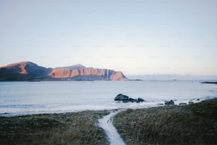 Ein Strand mit einem Gewässer und Bergen im Hintergrund