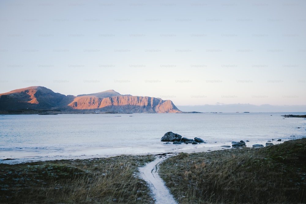 a beach with a body of water and mountains in the background