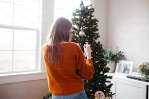 uma mulher segurando um controle remoto na frente de uma árvore de Natal