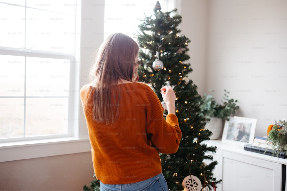 a woman holding a remote control in front of a christmas tree