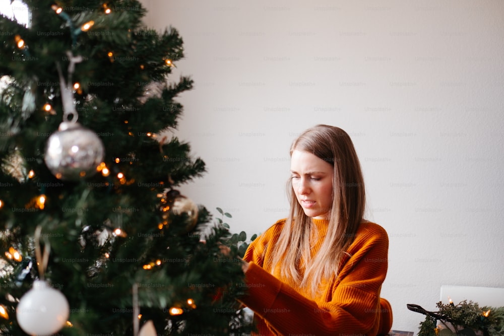 Una mujer sentada junto a un árbol de Navidad