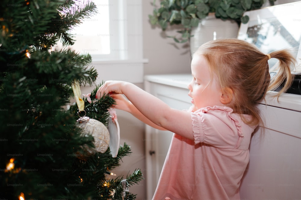 Une petite fille touchant un sapin de Noël