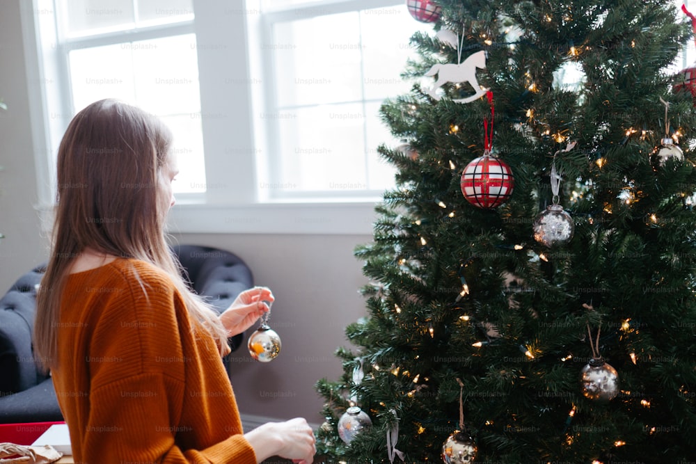 Eine Frau sitzt neben einem Weihnachtsbaum