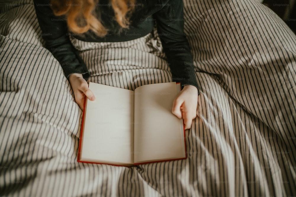 une personne allongée sur un lit en train de lire un livre