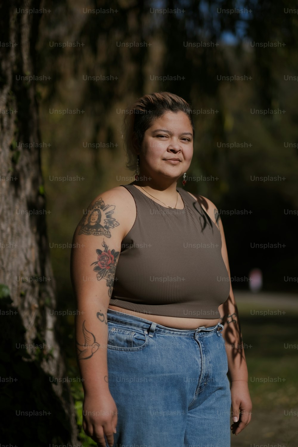 a person with tattoos standing next to a tree