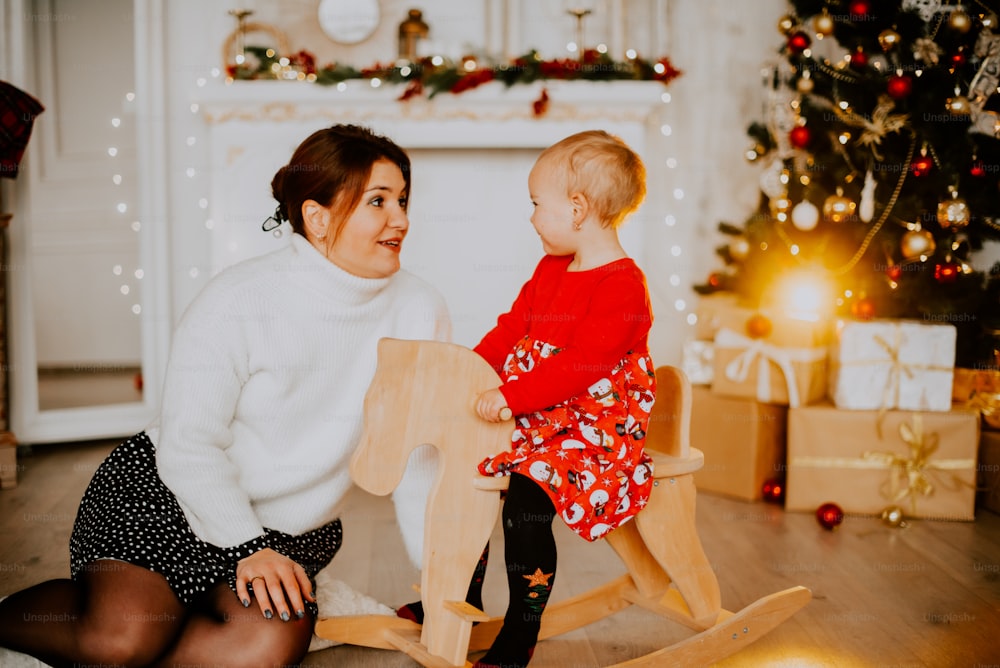 a woman and a child sitting on a couch in front of a christmas tree