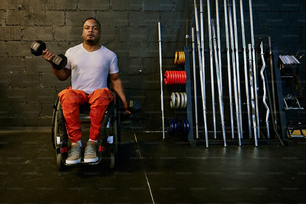 Un hombre sentado en una silla de ruedas sosteniendo una botella y una lata