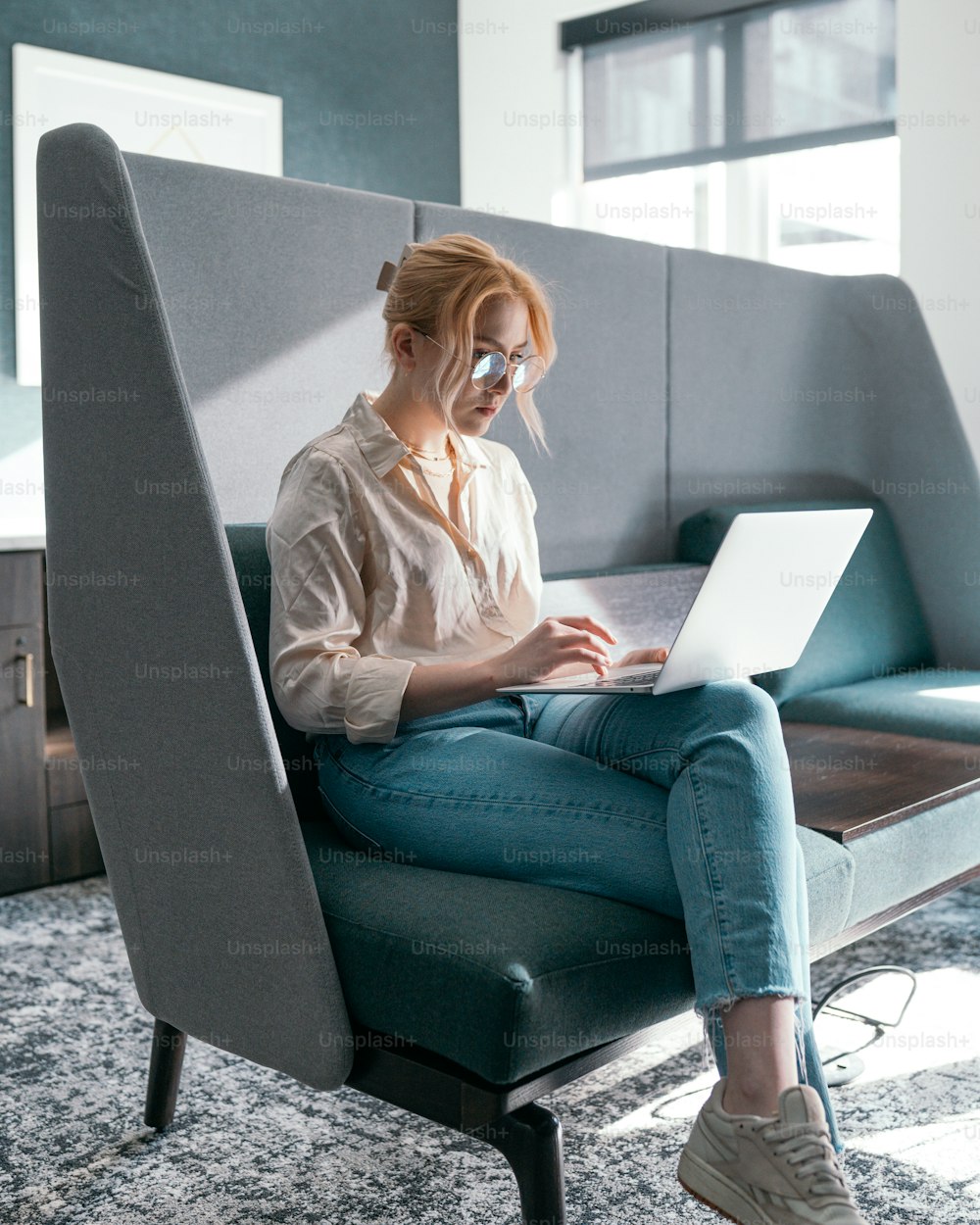 uma mulher sentada em uma cadeira com um laptop