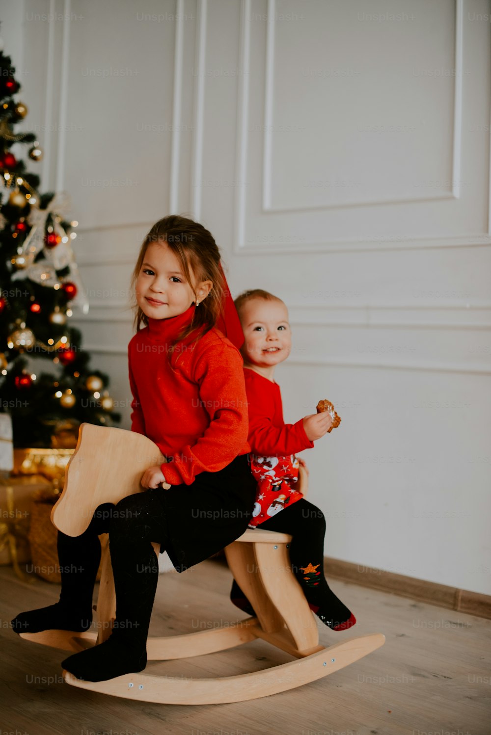 a woman and a child sitting on a chair in front of a christmas tree