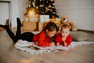 Una persona e un bambino seduti sul pavimento di fronte a un albero di Natale