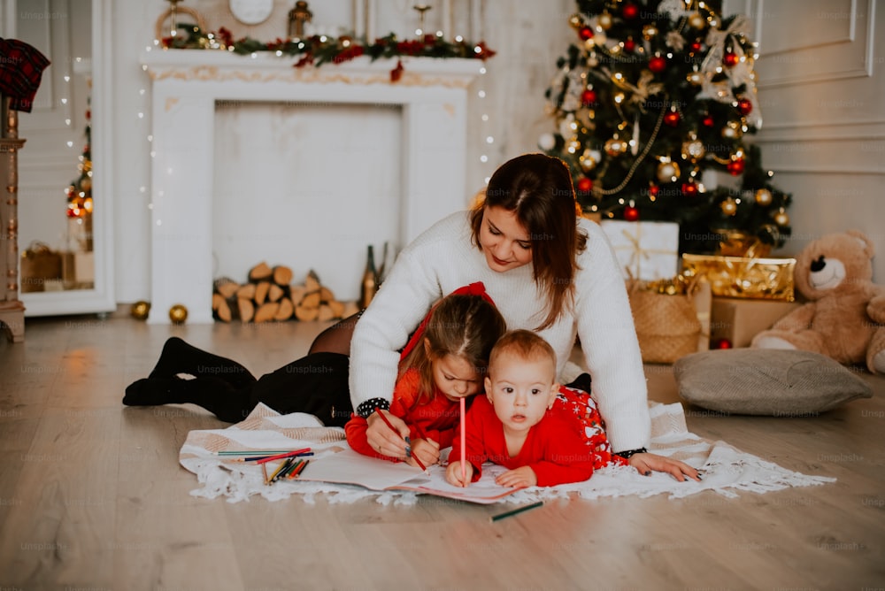 Une personne et un enfant lisant un livre devant un sapin de Noël