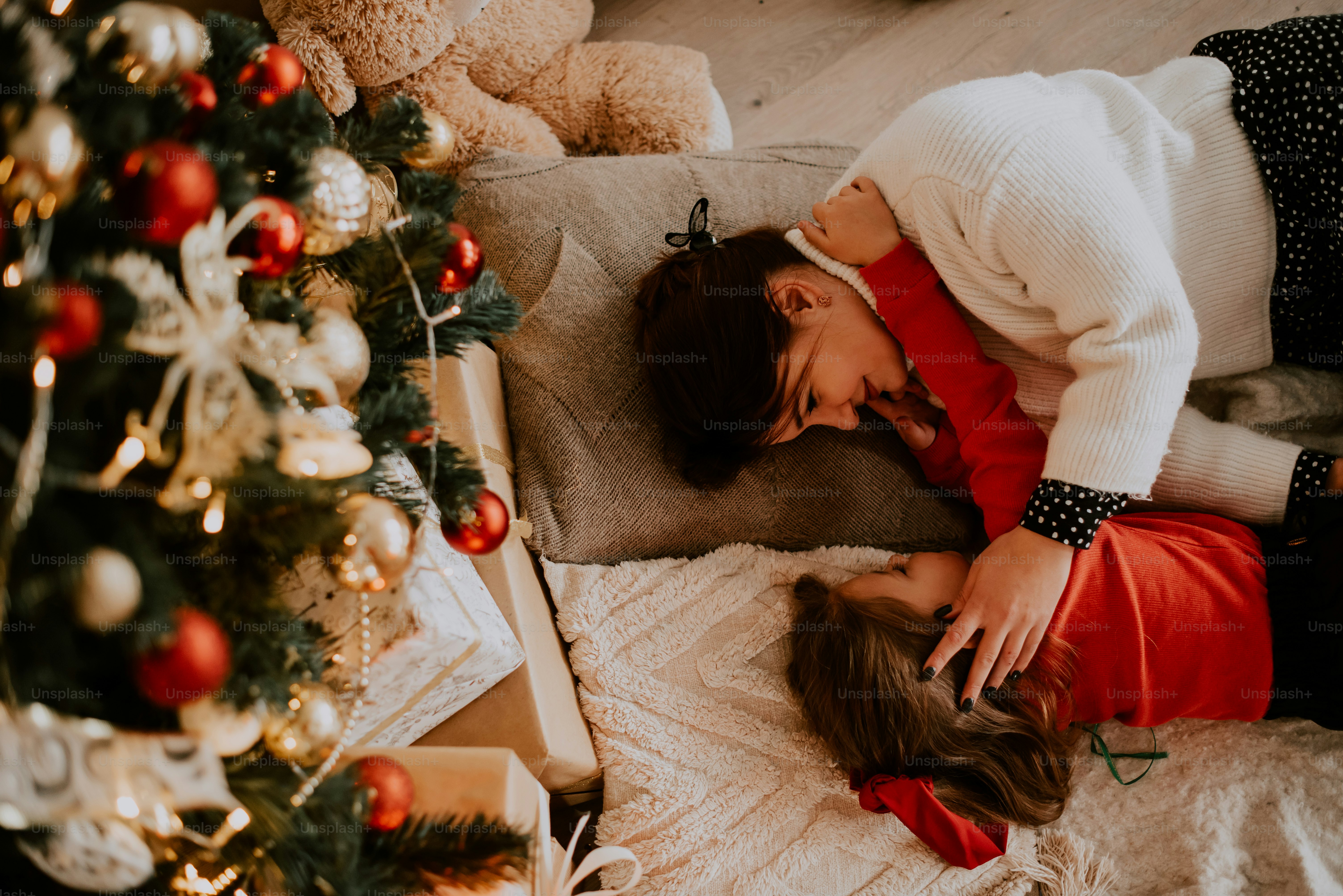a man and woman kissing in front of a christmas tree
