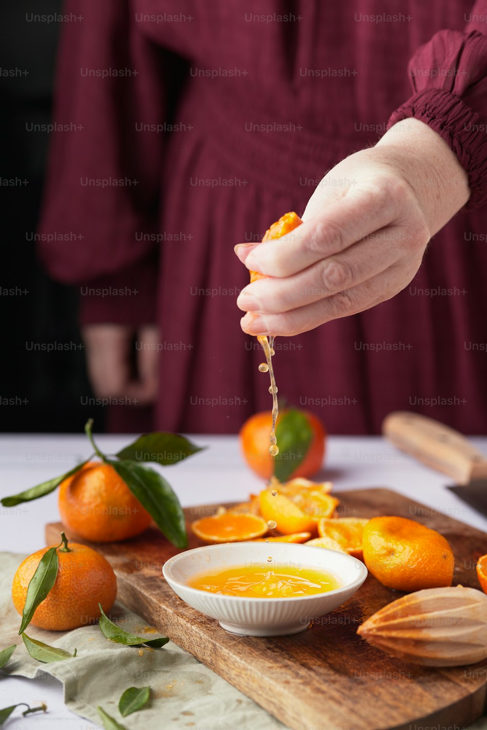 a person pouring a liquid into a bowl of oranges