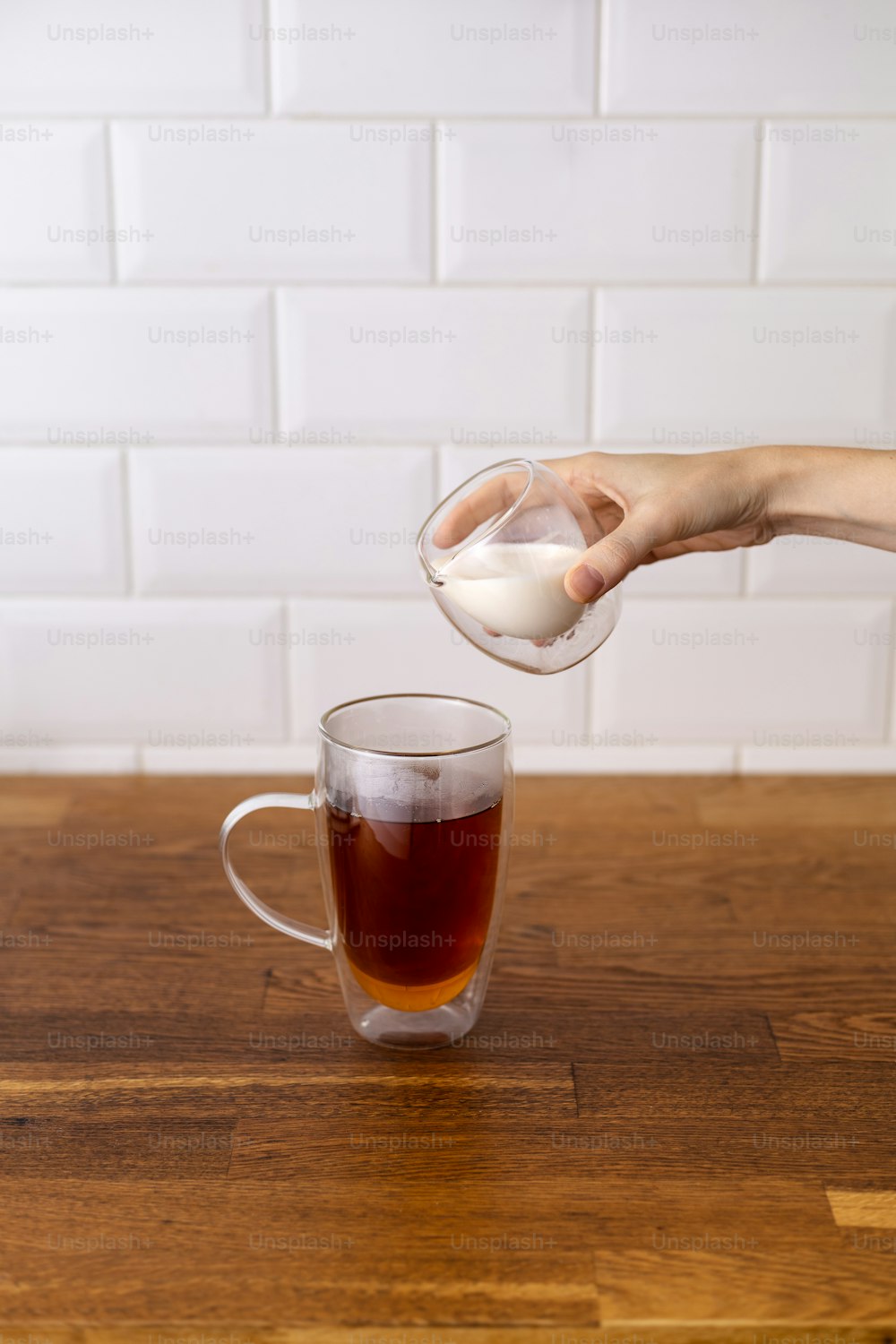 a hand pouring a glass of liquid into a glass