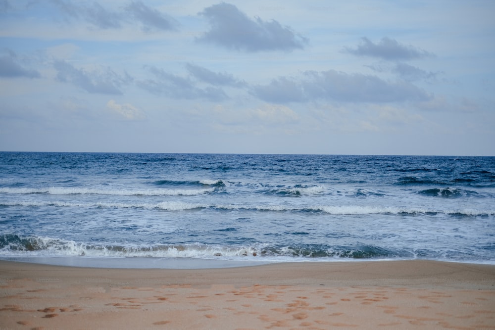 a beach with waves and clouds