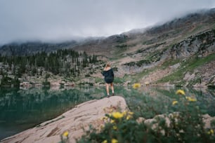 uma pessoa correndo em uma trilha por um lago com árvores e montanhas ao fundo
