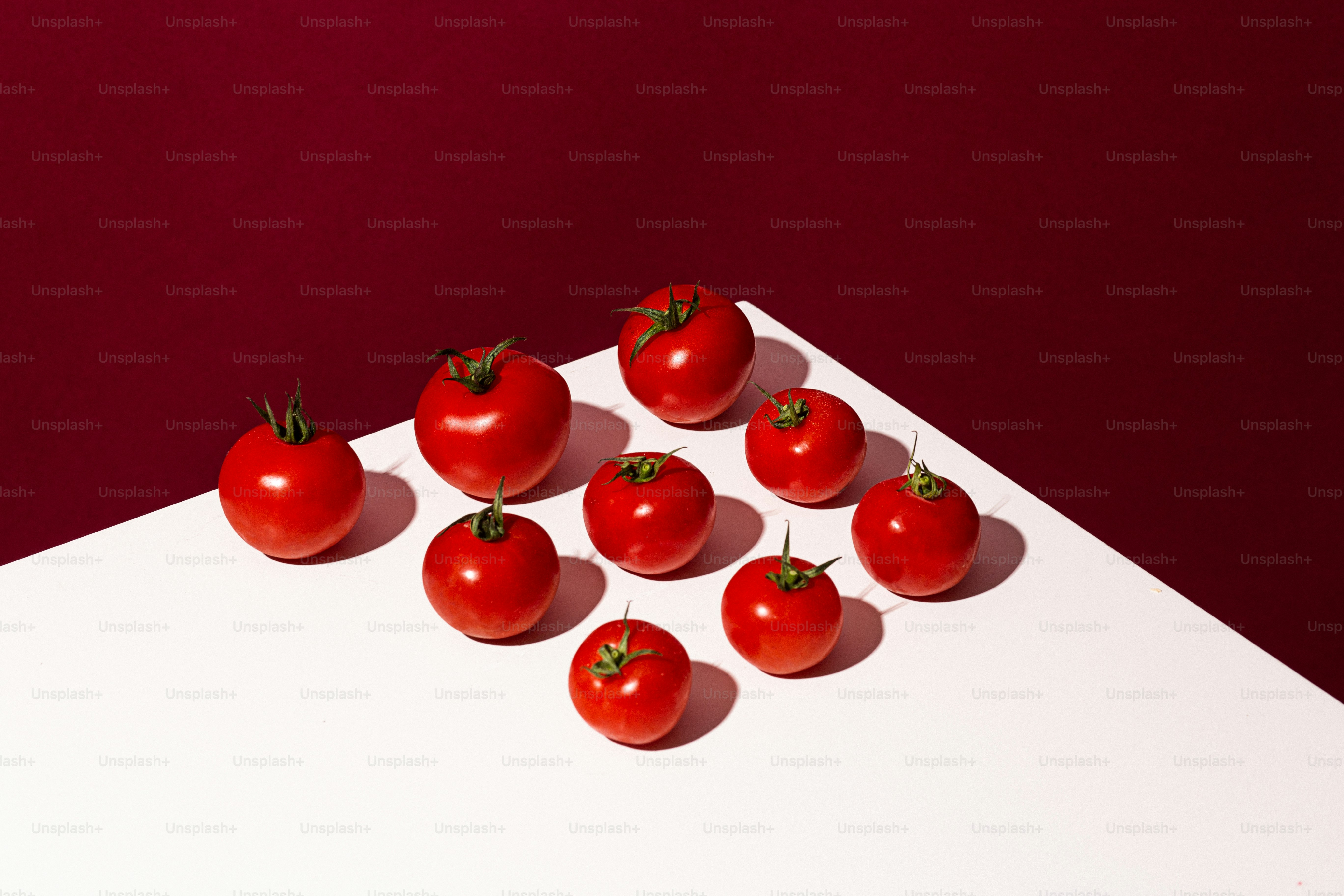 A few tomatoes on a white table with red background