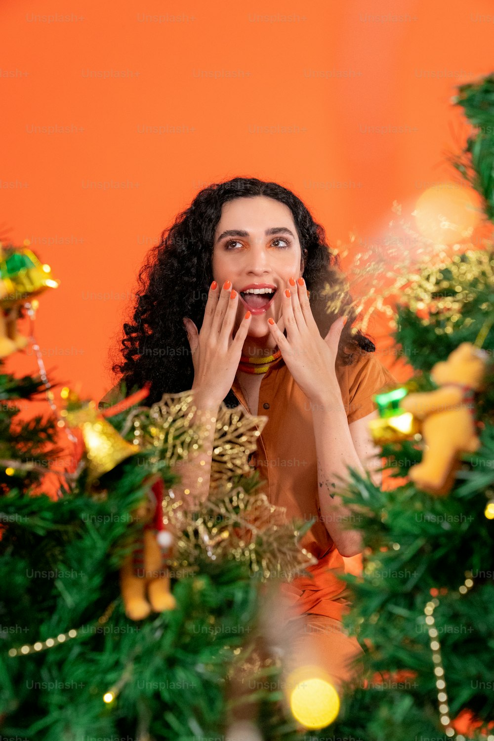 Una persona con las manos en la cara frente a un árbol de Navidad