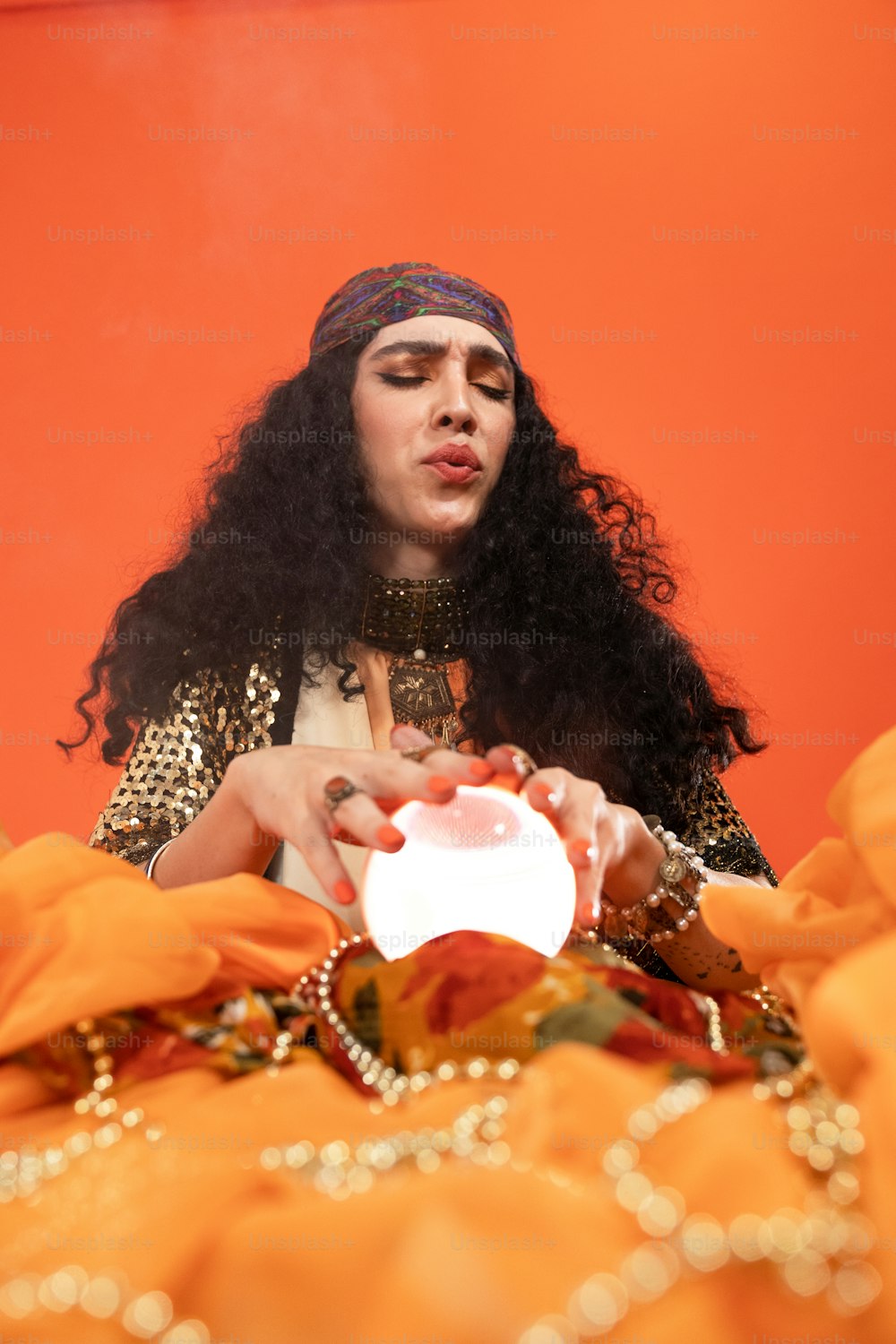 a person wearing a headdress holding a white bowl of gold