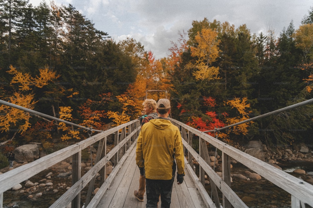 um homem e uma mulher andando em uma ponte sobre um rio