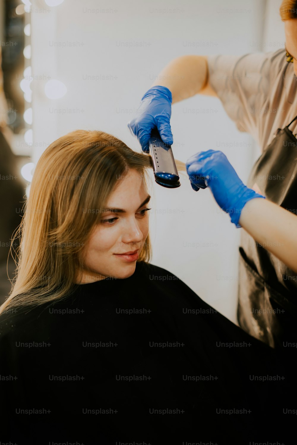 Estilista arreglando el peinado con laca para el cabello en un salón de  belleza
