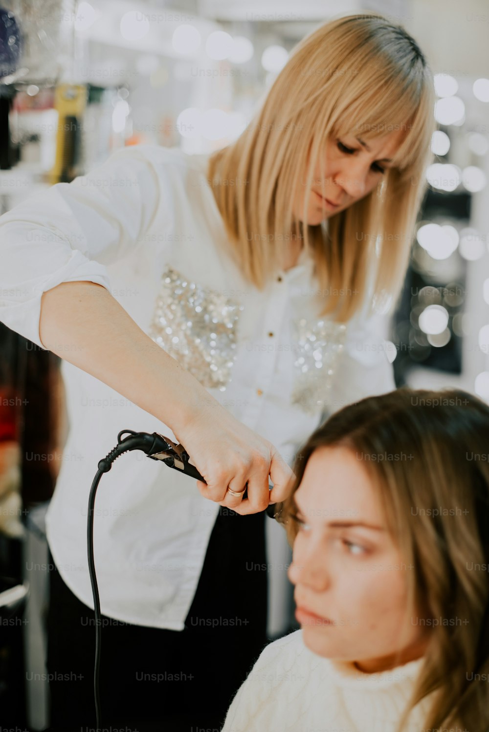 uma mulher cortando o cabelo de outra mulher em um salão de beleza