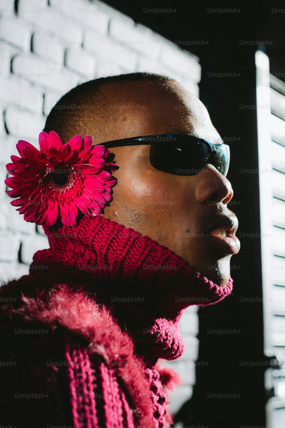 a person wearing sunglasses and a red flower in the hair