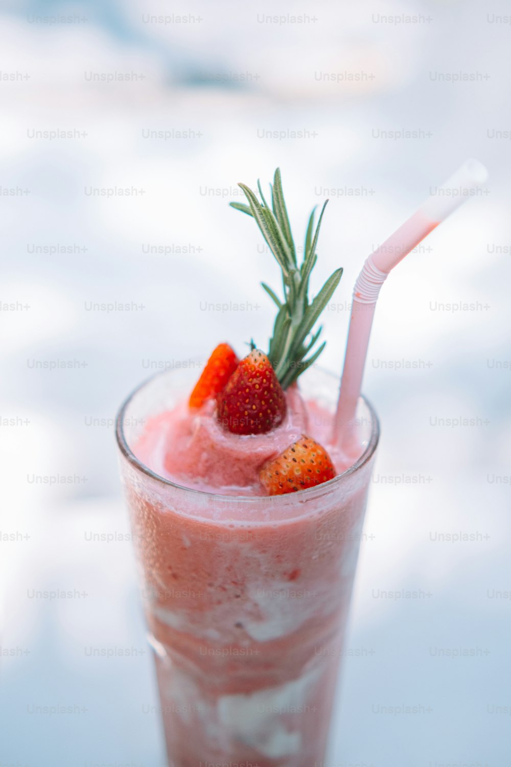 a glass with a drink and strawberries in it