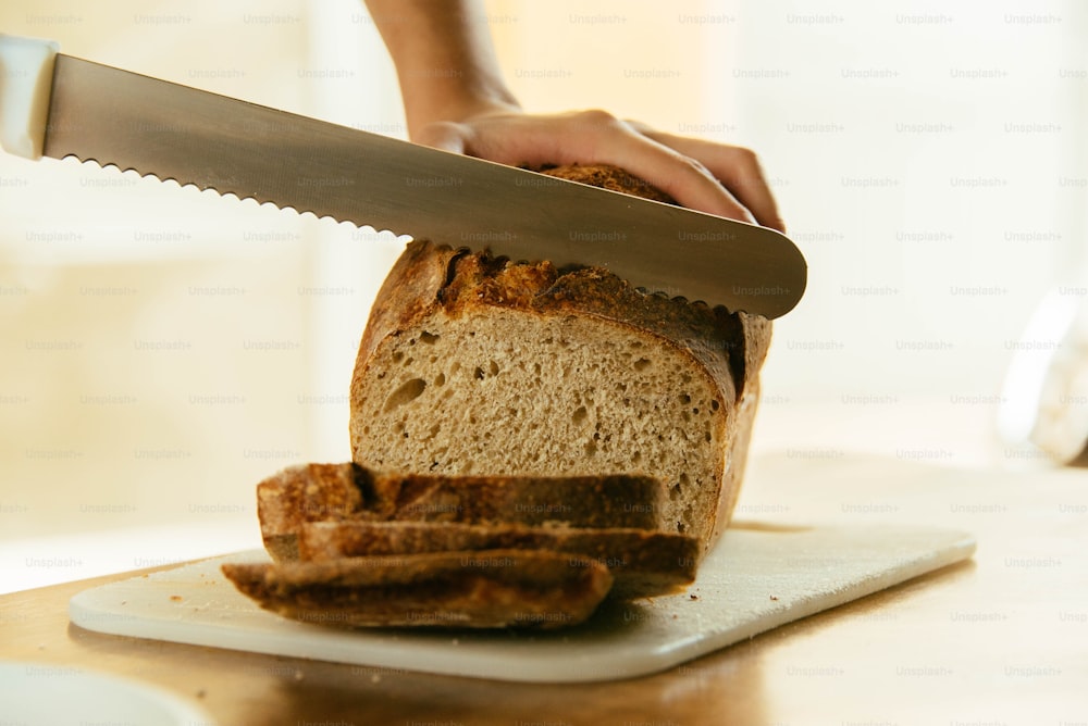 a person slicing a loaf of bread