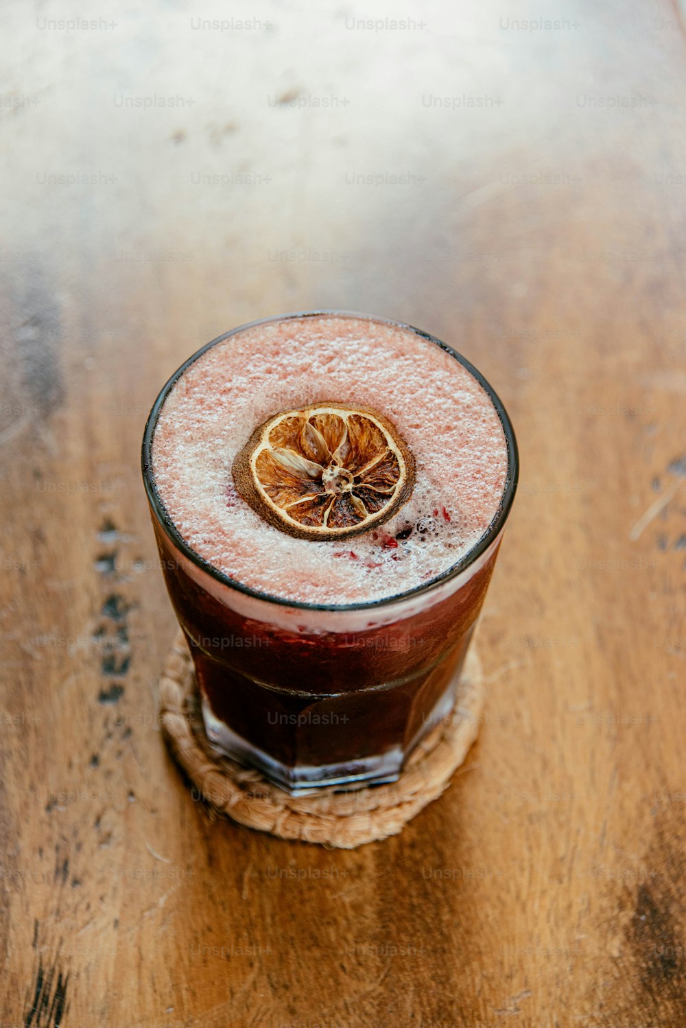 a glass of red liquid with a slice of lemon on top